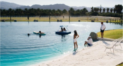Friends wading into a resort pool together at golden hour, one paddling a small boat